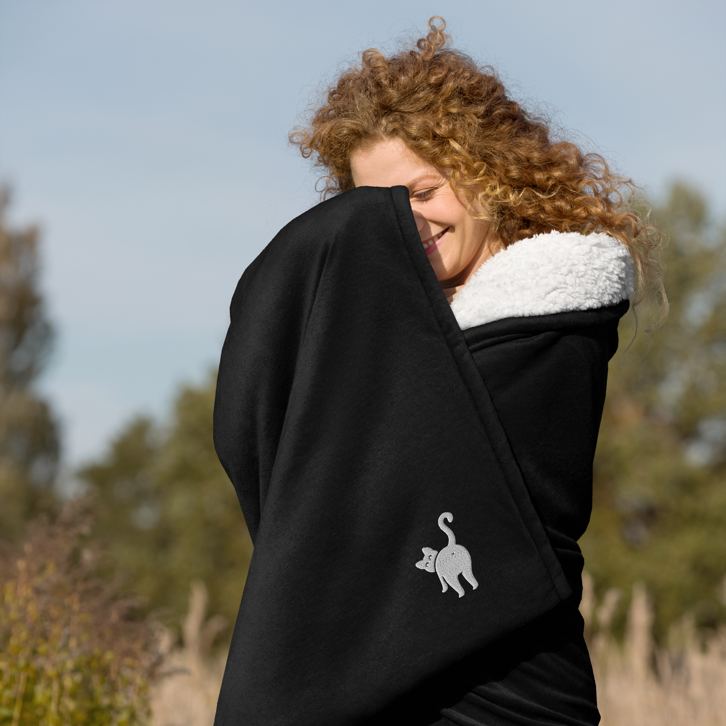 Person wrapped in a black blanket with a cat logo - black