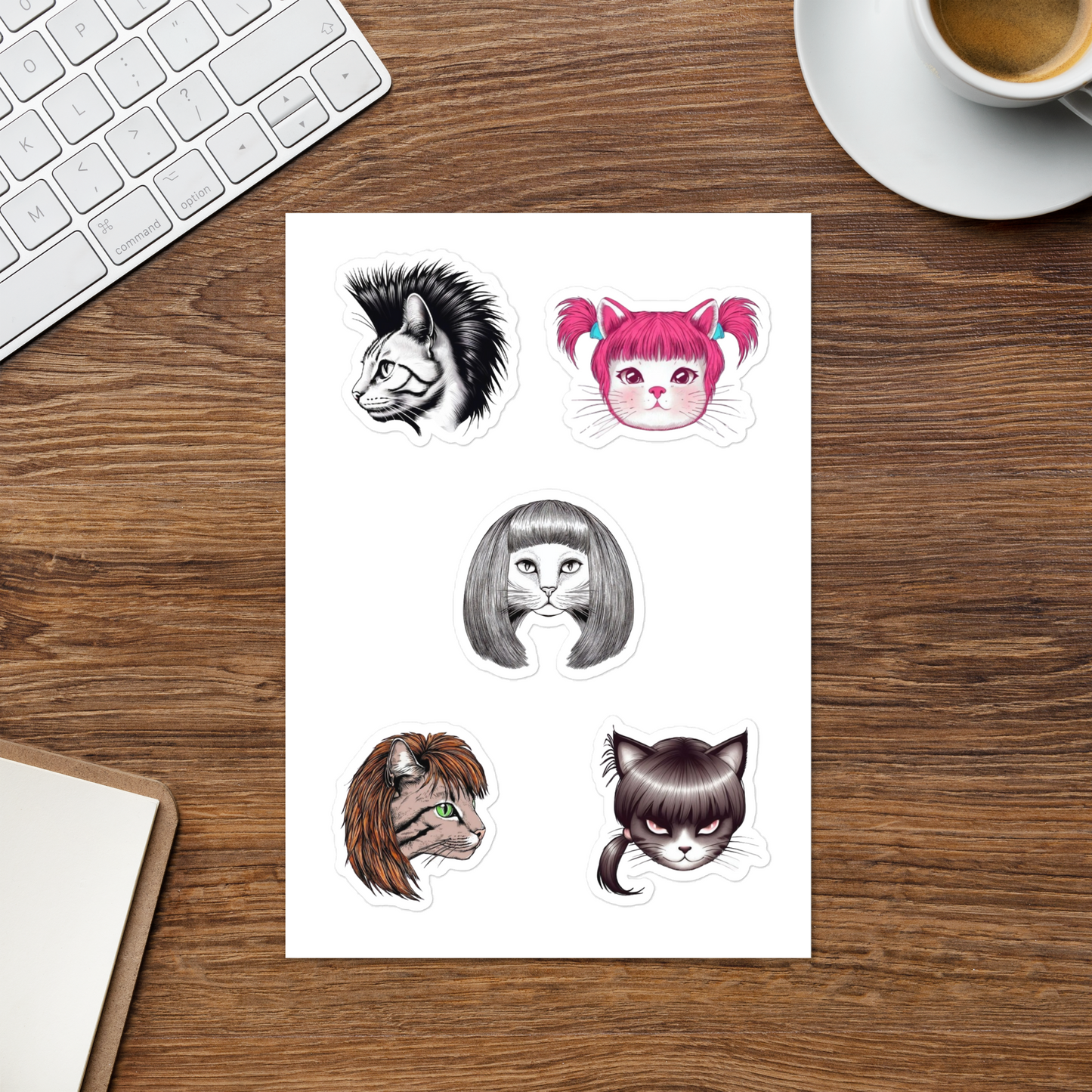 Sheet of cat-themed temporary tattoos on a wooden desk with a keyboard and coffee cup.