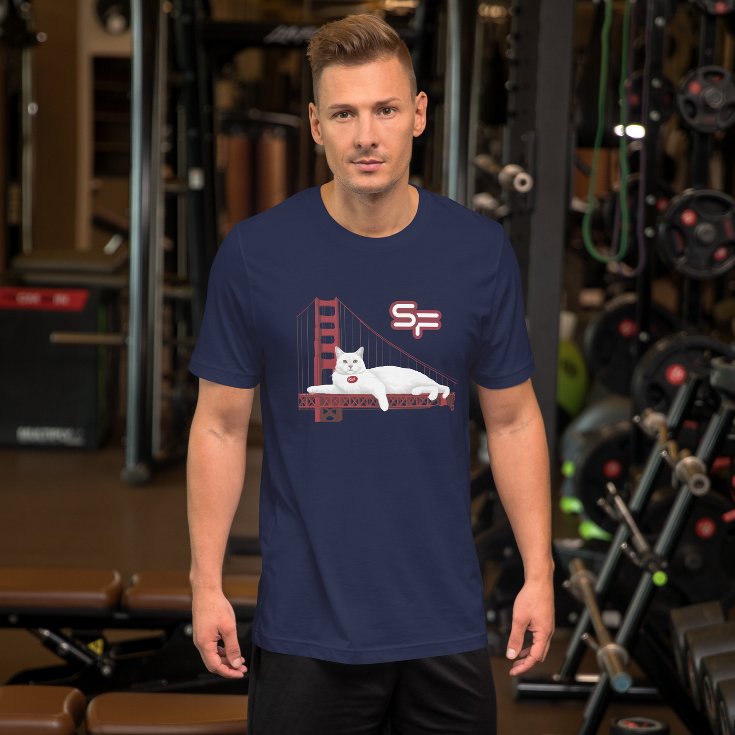 Man wearing a navy blue t-shirt with a graphic design of a cat on a bridge in a gym setting - navy