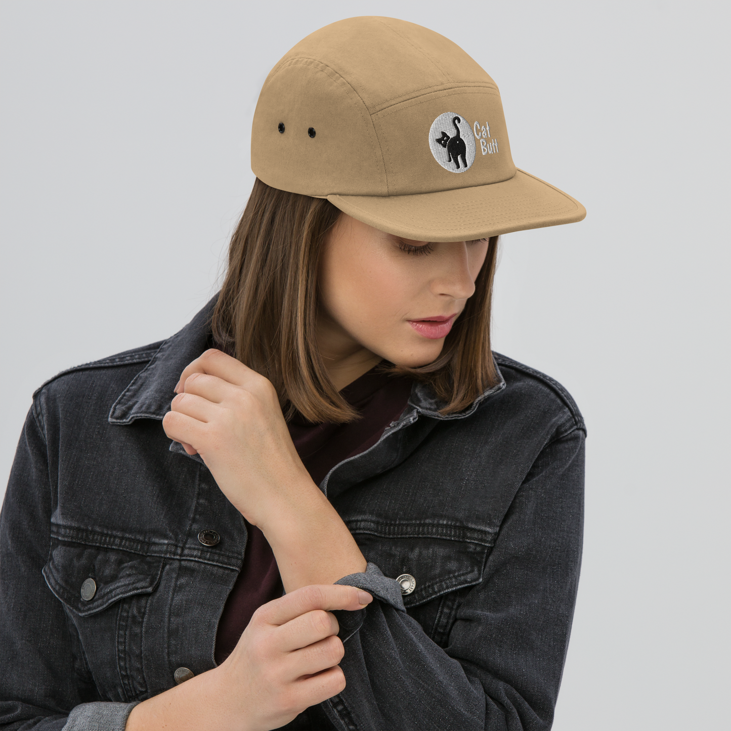 Person wearing a beige cap with a logo on a plain background - khaki