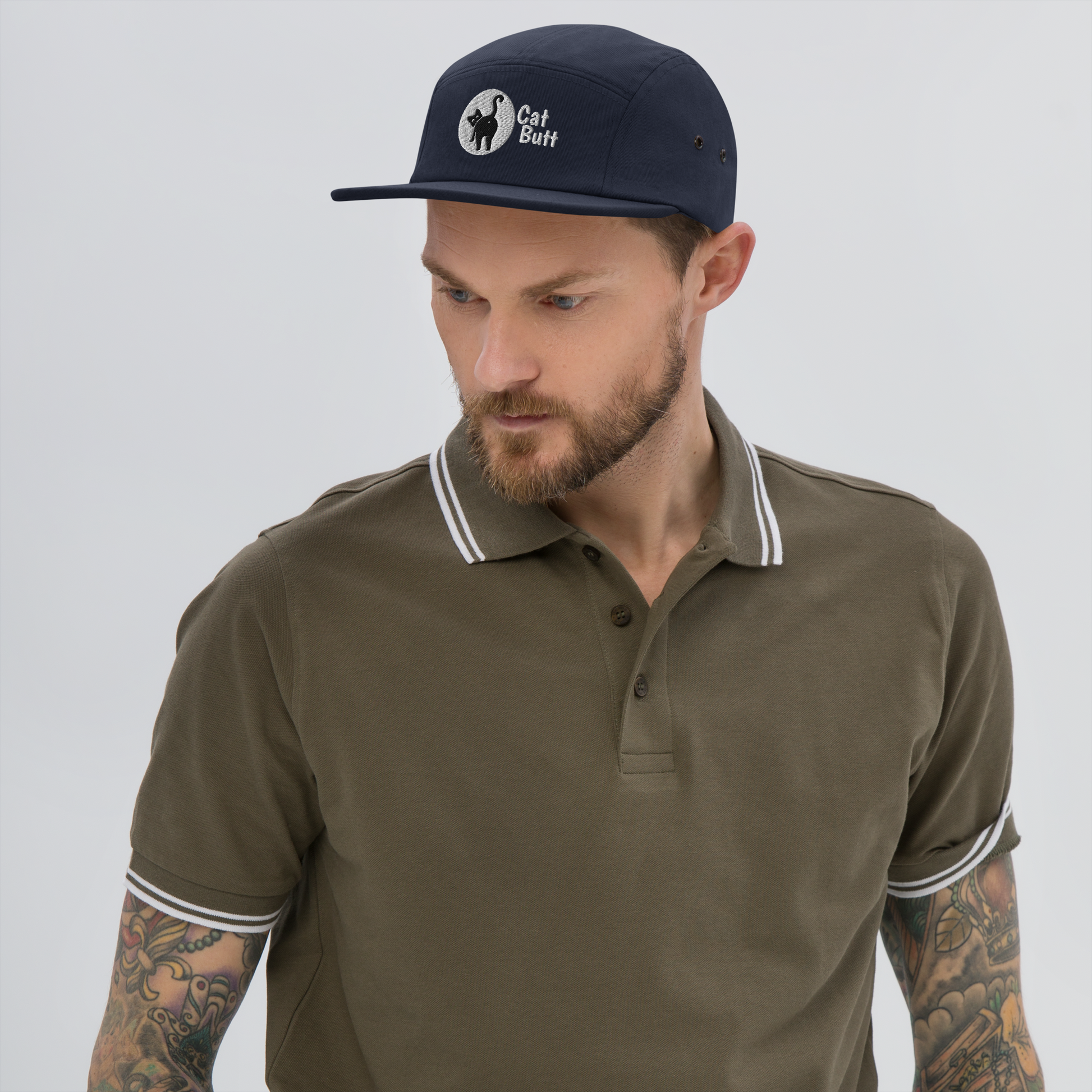 Man wearing a brown polo shirt and navy cap with a logo on a gray background - navy