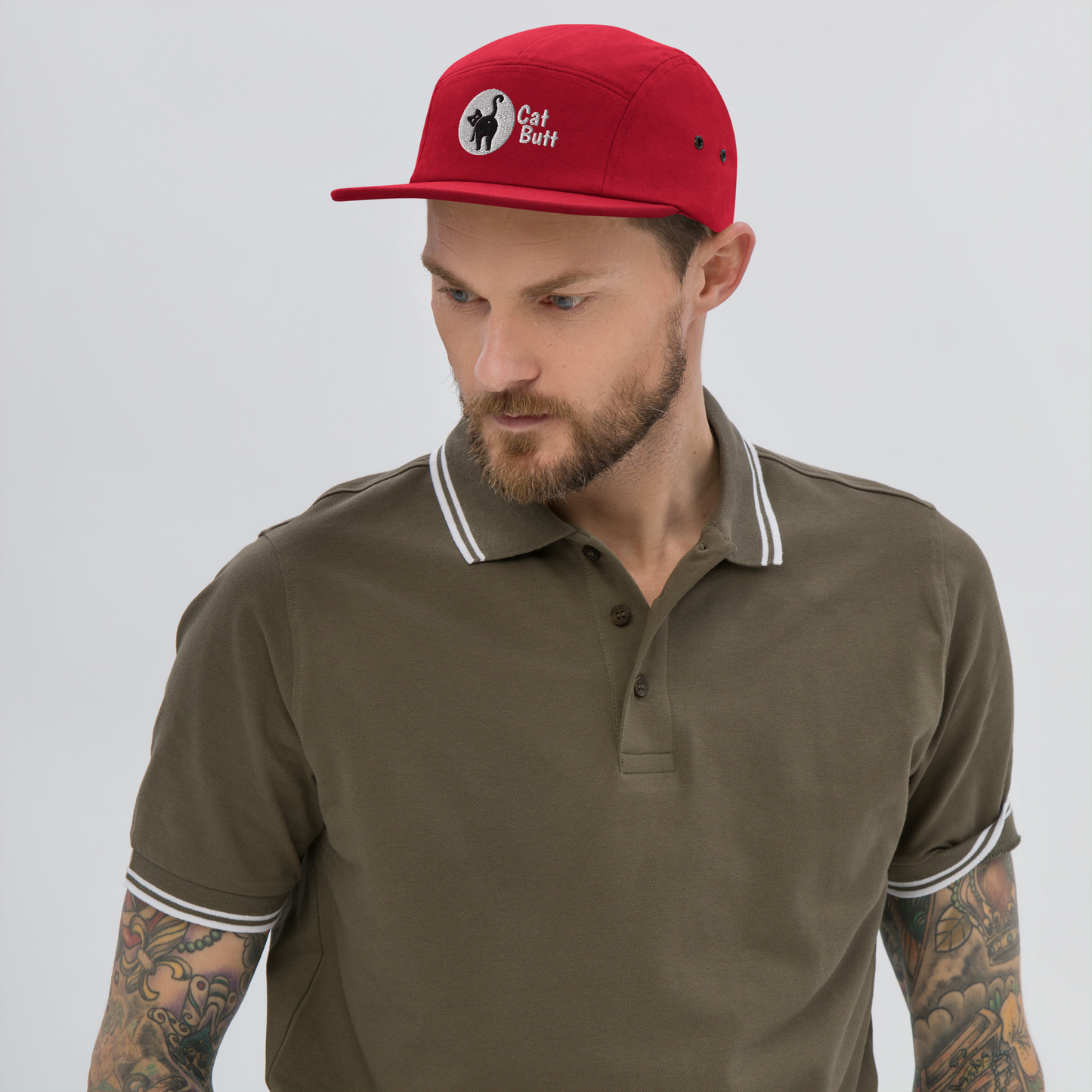 Man wearing a red cap with a logo and a brown polo shirt on a gray background - red