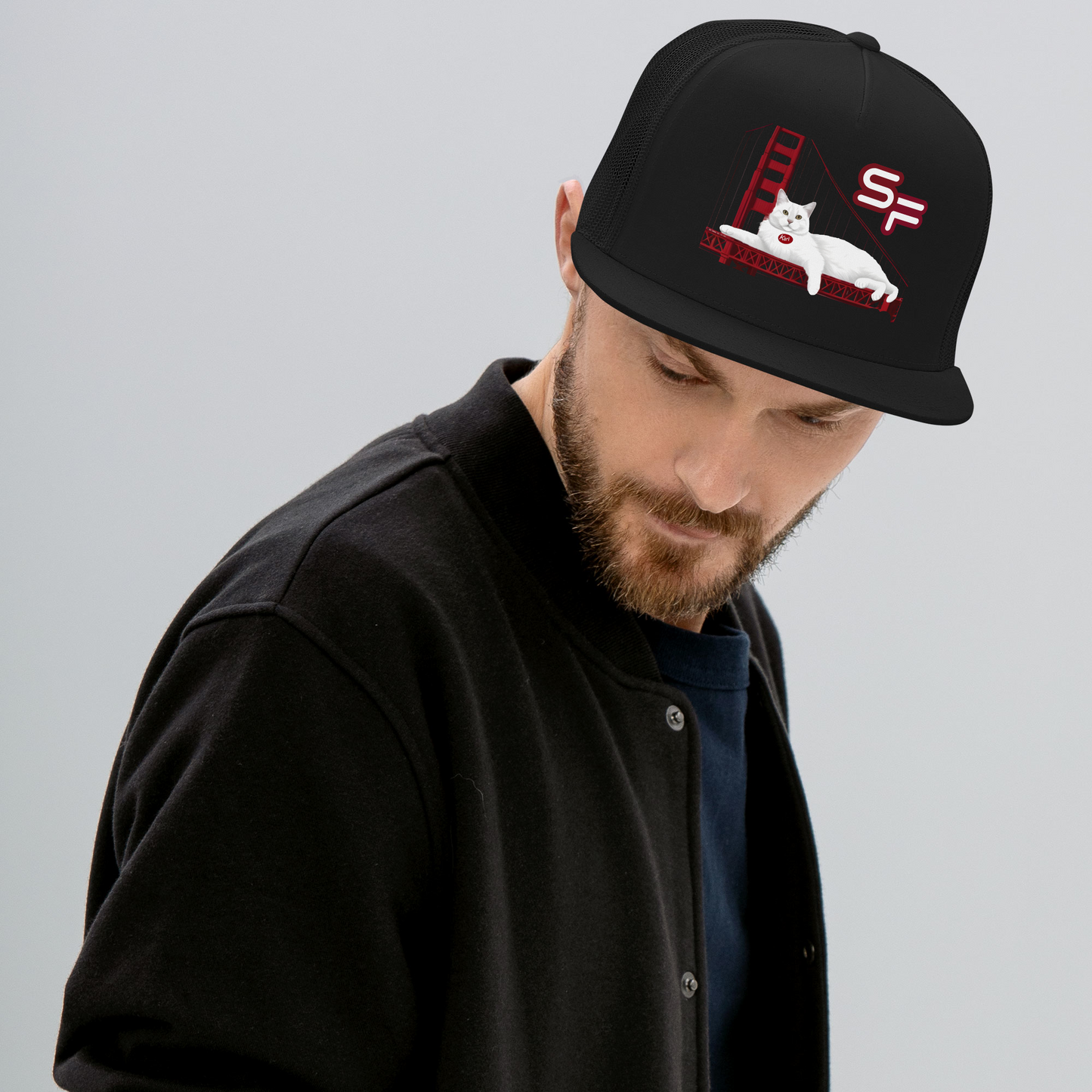 Man wearing a black cap with a design of a cat and 'SF' on a gray background