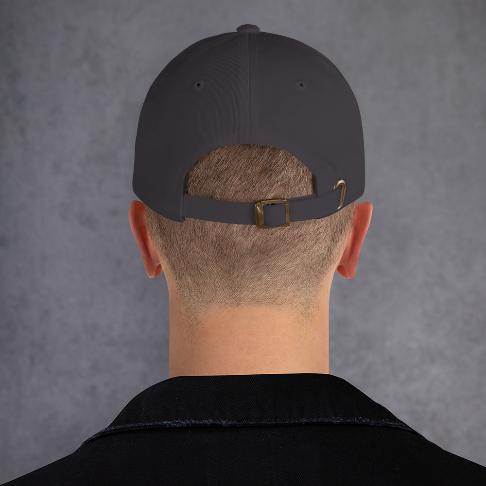 Person wearing a black cap with a brown buckle on a gray background - dark grey