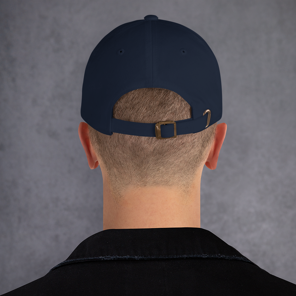 Person wearing a navy blue cap with a brown buckle on a gray background - navy