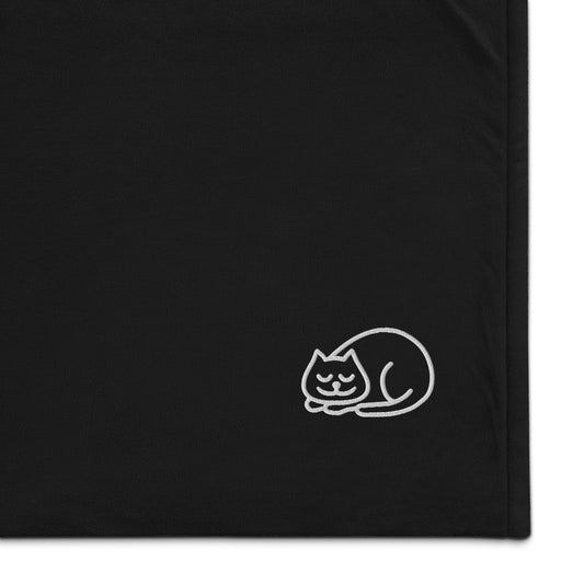 The corner of a sherpa blanket with a cute sleeping cat embroidered onto it - Black