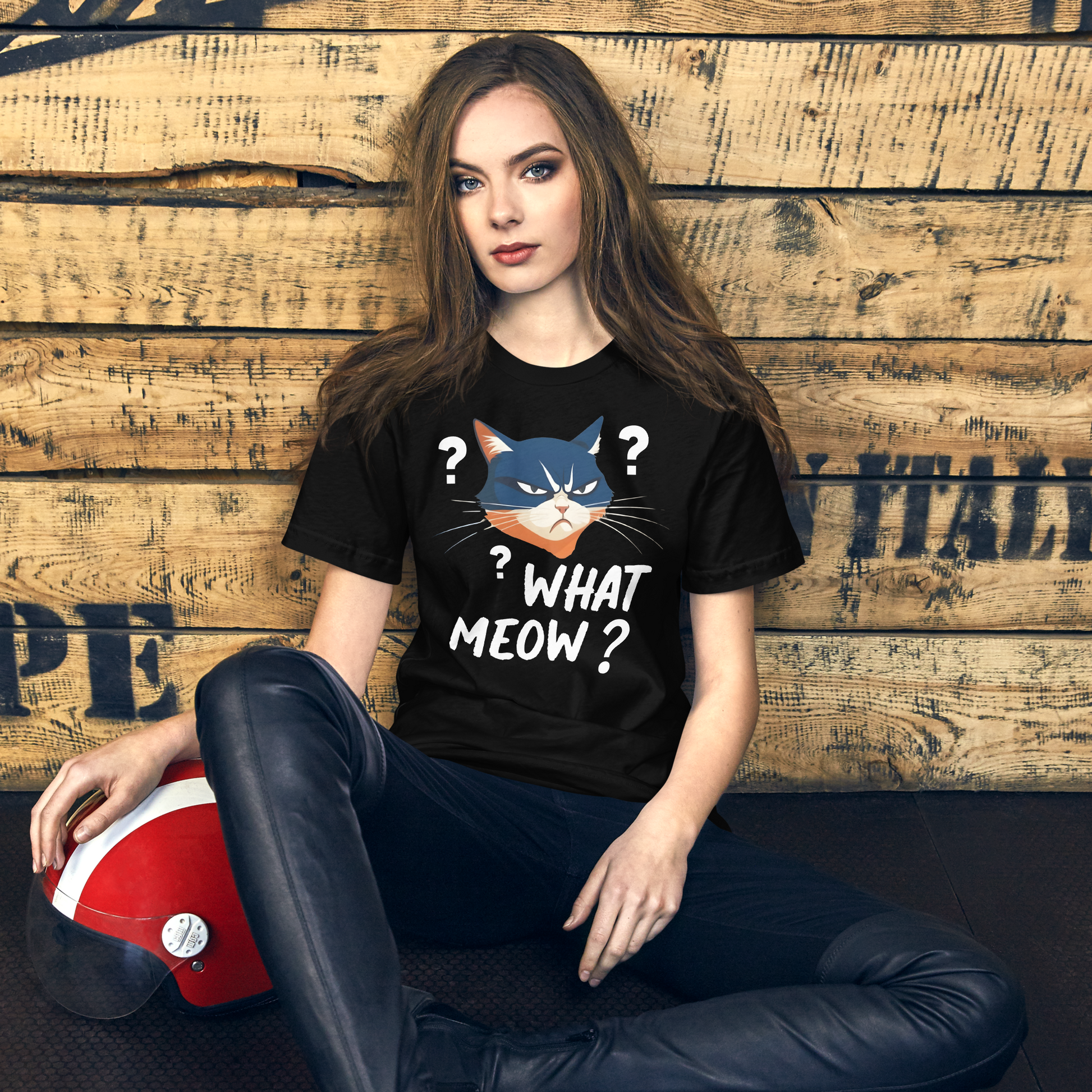 Woman wearing a black t-shirt with a cat graphic and text, sitting against a wooden wall. - black