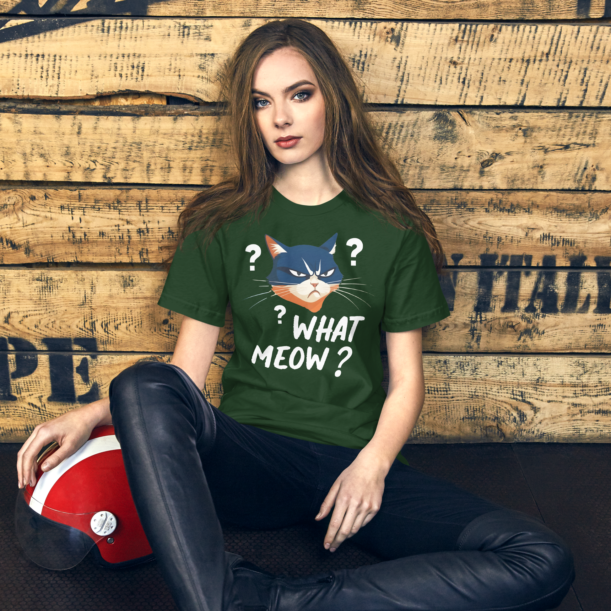 Woman wearing a green t-shirt with a cat graphic and text, sitting against a wooden wall. - forest
