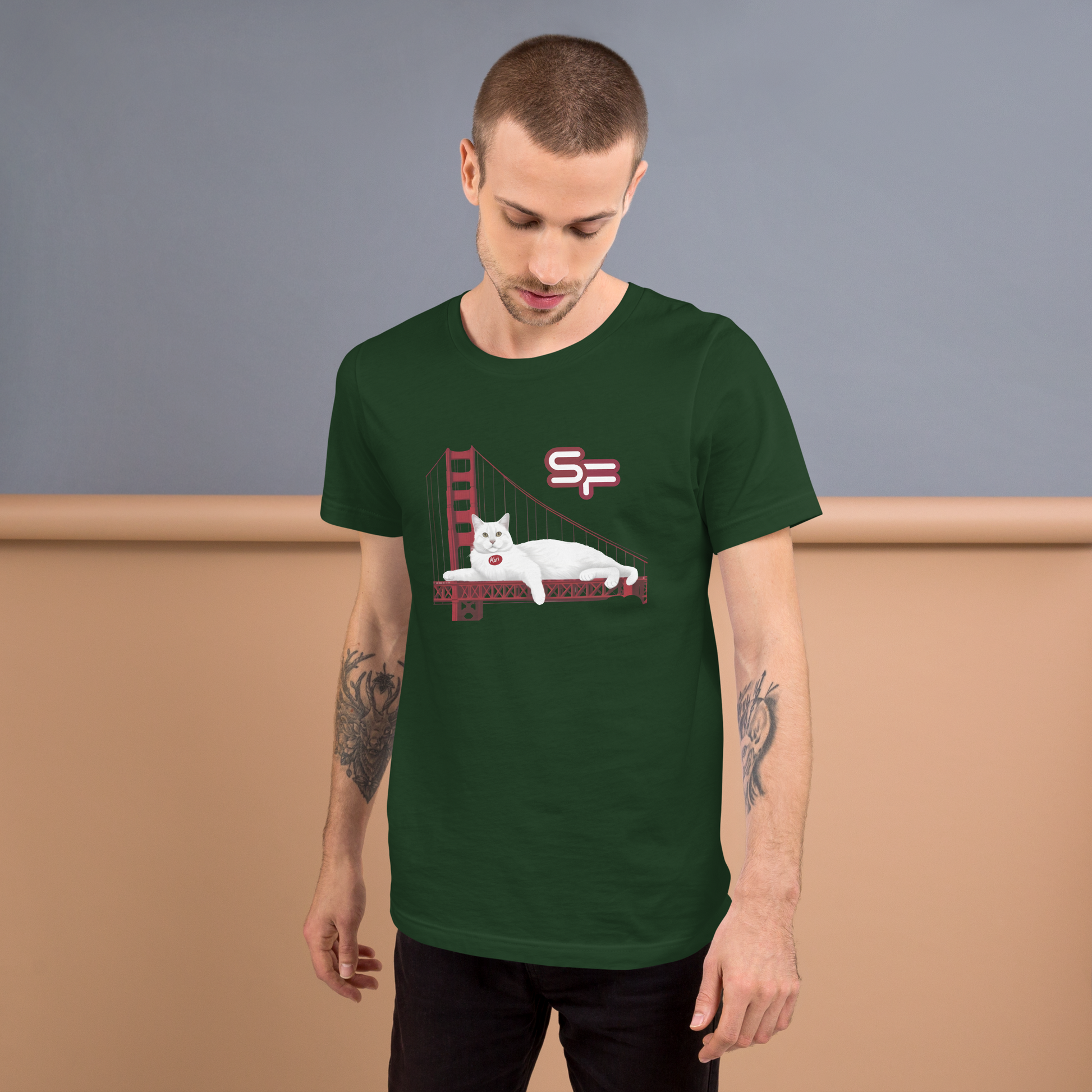 Man wearing a green t-shirt with a graphic design of a cat on a bed with a Golden Gate Bridge and 'SF' logo. - forest
