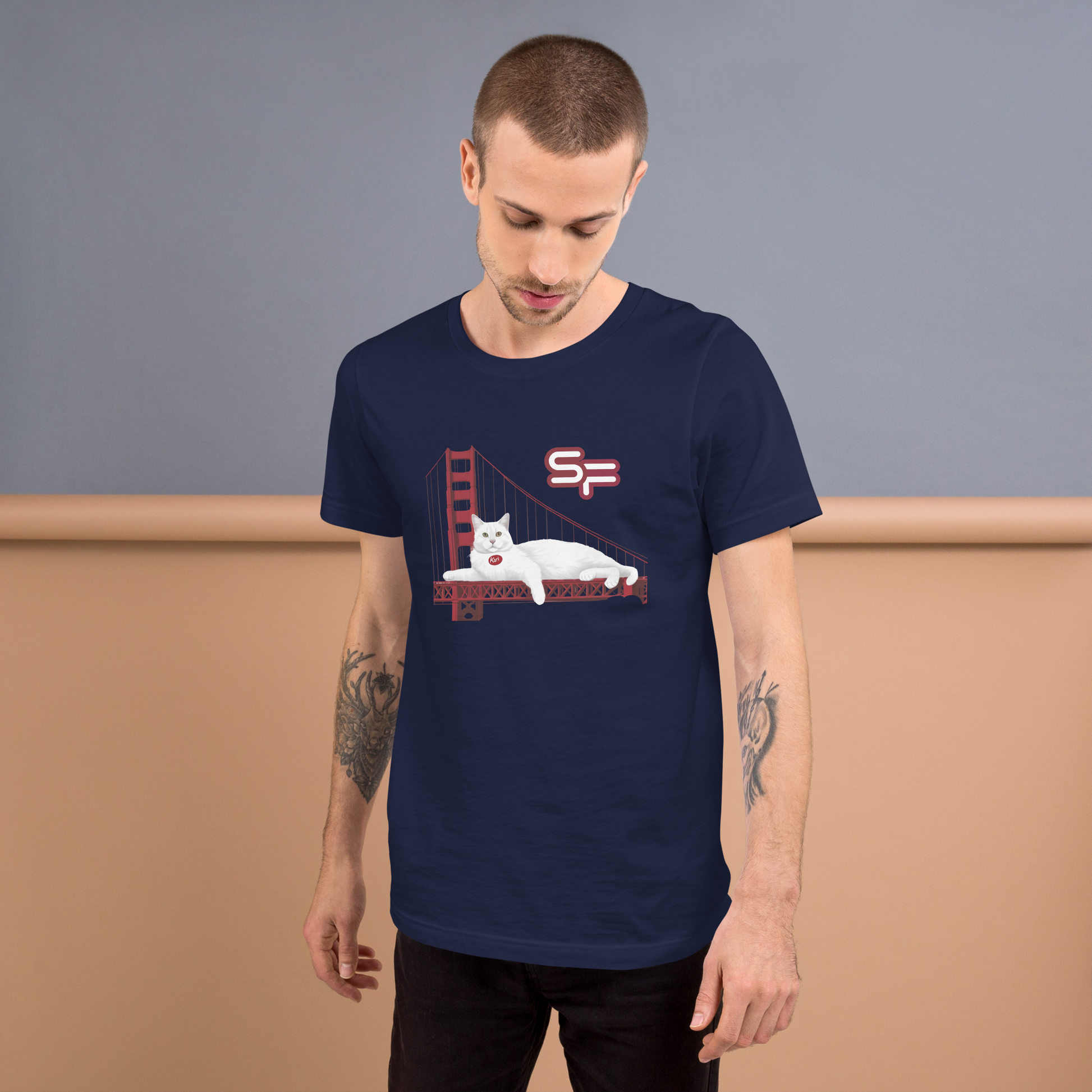 Man wearing a navy blue t-shirt with a graphic design of a cat on a bed with a cityscape in the background. - navy