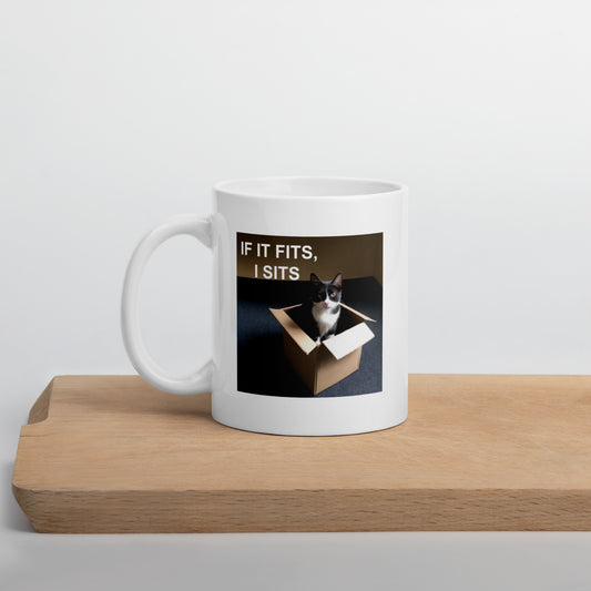 A white glossy mug with a cat meme about sitting in boxes on a piece of mid century modern wood - 11 oz